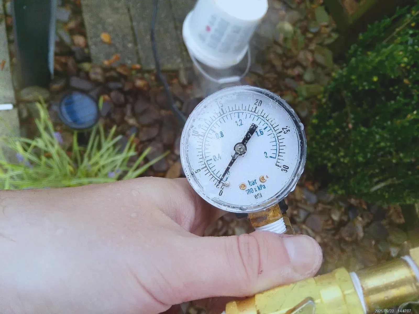 Hand holding a pool pump pressure gauge showing the reading at 1psi.